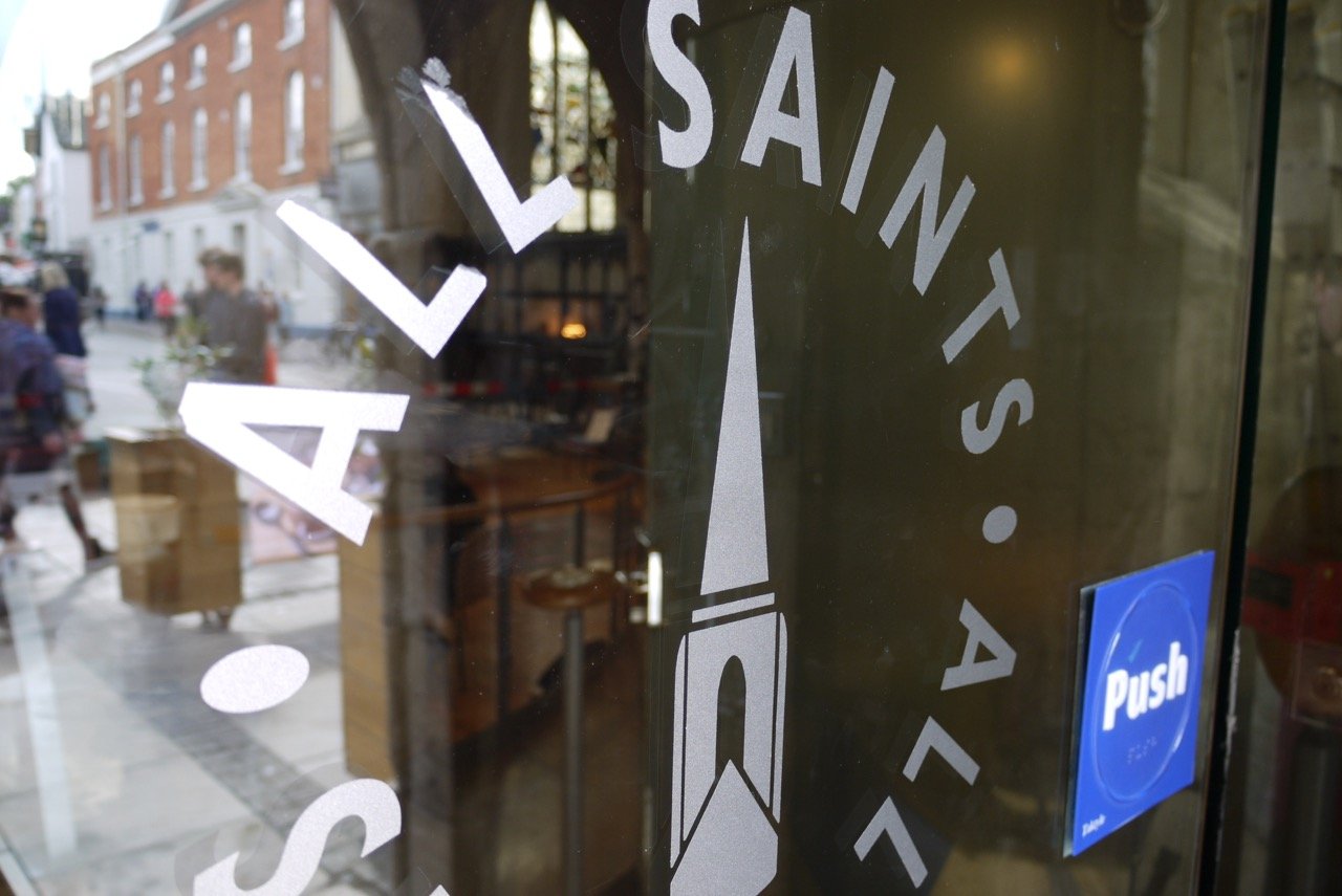 The words 'All Saints' etched on the glass entrance door of the church.