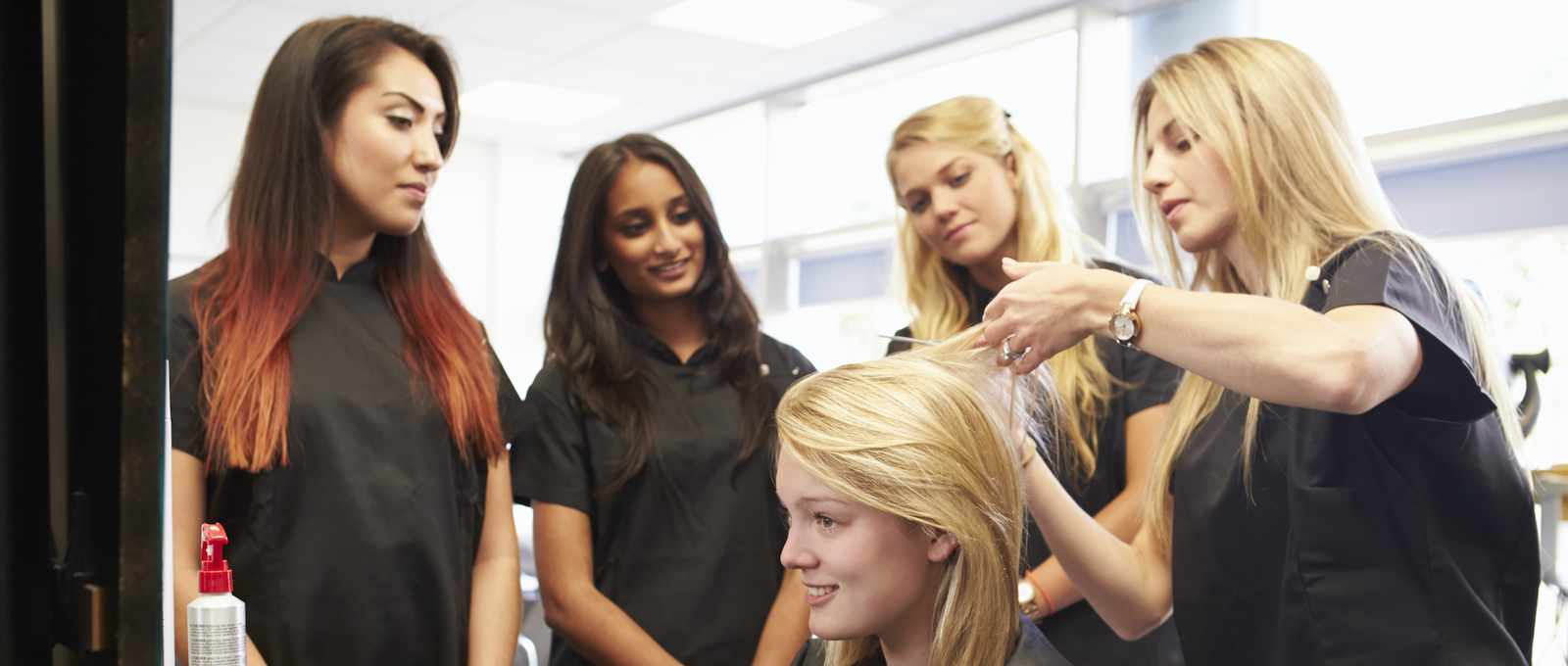 Hairdressing students style a model's hair under a tutor's guidance at Horizon Training.