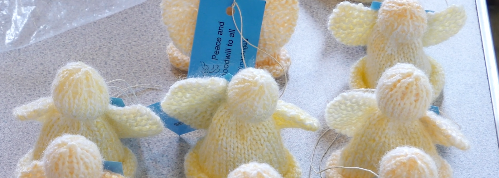 Three small hand-knitted lambs in cream and yellow wool laid out on a table.