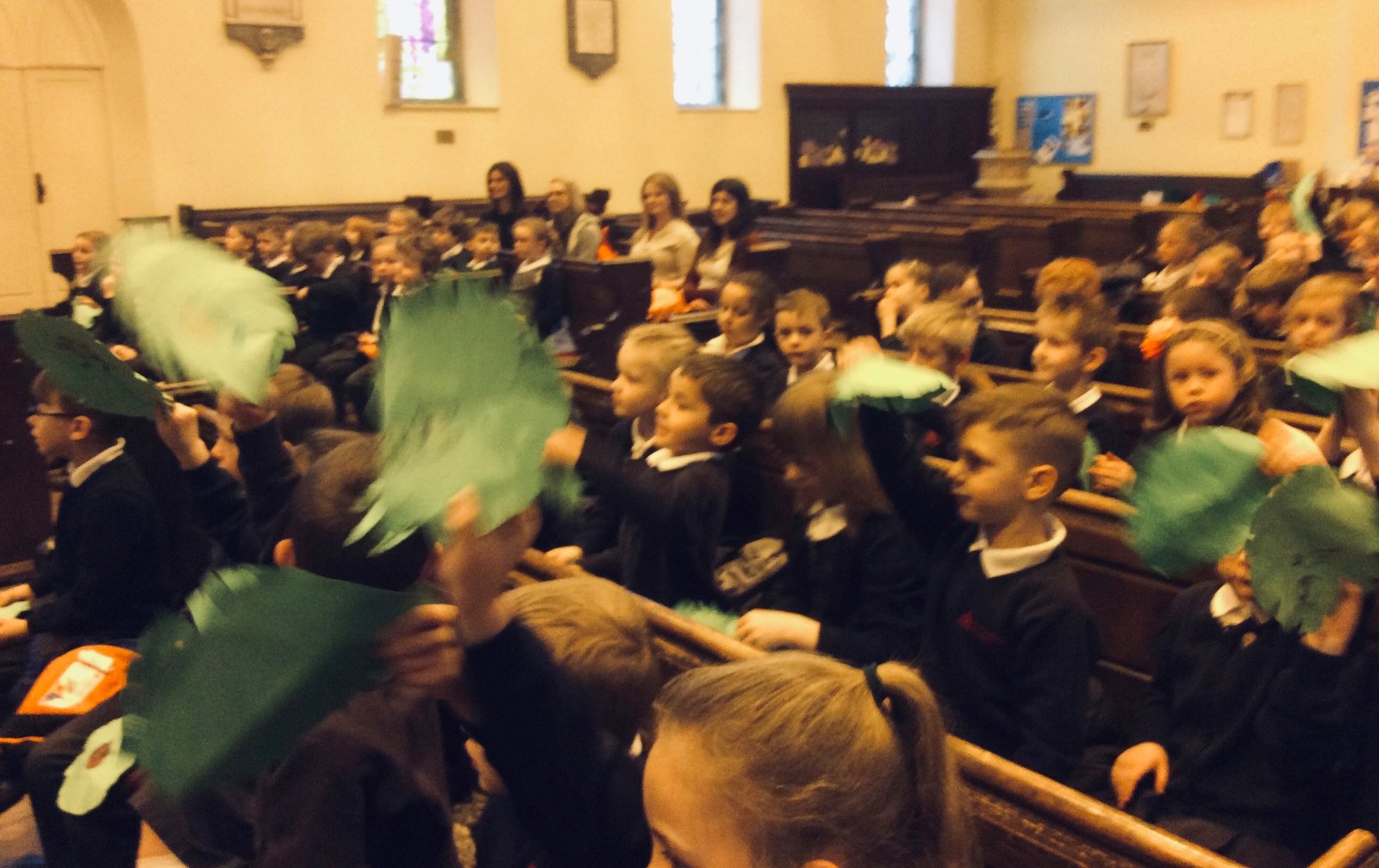 Children wave green palm branches in the pews during a Palm Sunday service.