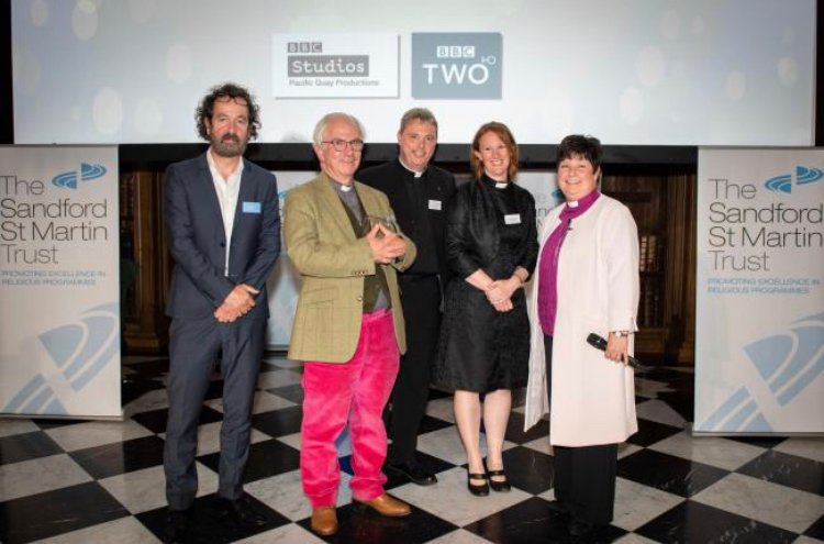 Five people pose at an awards event in front of BBC Studios and Sandford St Martin Trust banners.