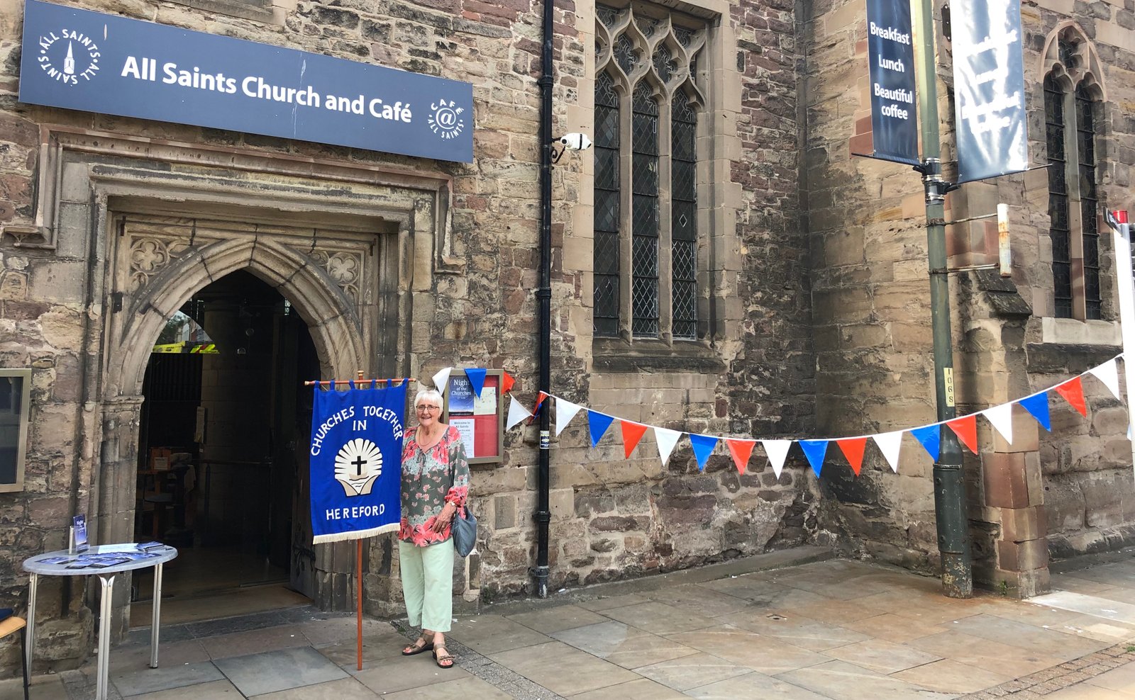 All Saints Church and Cafe entrance decorated with bunting and a welcome sign table.