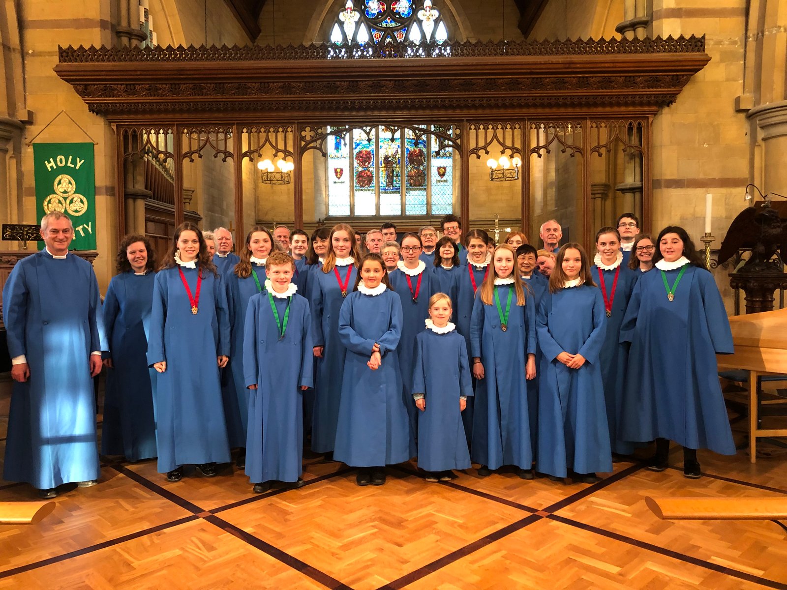 The Holy Trinity Church choir poses together in the church wearing blue robes.