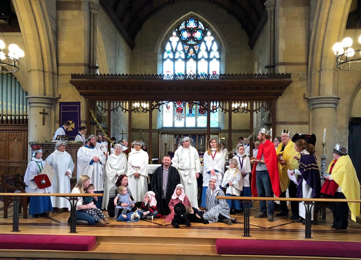 A large group of children and adults dressed as nativity characters pose together in church for a crib service.