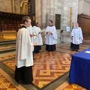 New curate in church robes with clergy in a cathedral