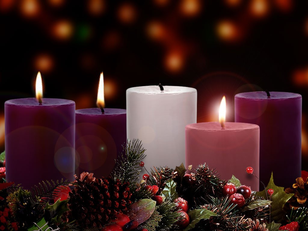 An Advent wreath of pine, pinecones and berries holding two lit purple candles, a lit pink candle and a lit white candle.