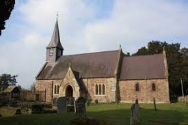 St. Mary's Church, a stone building with a spire, set in a churchyard on a sunny day.