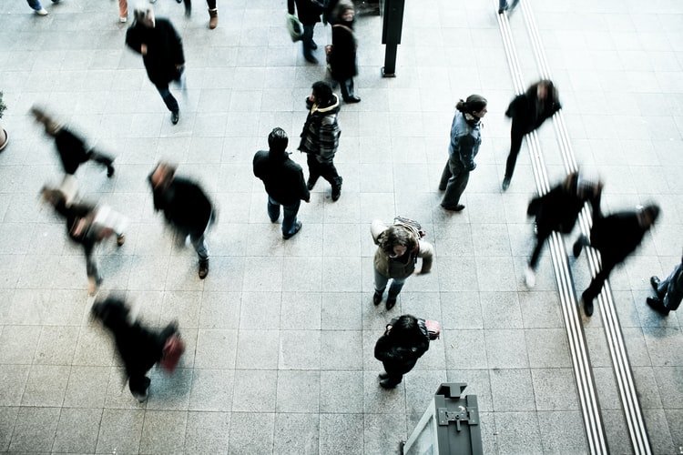 An aerial view of blurred figures walking across a paved plaza.