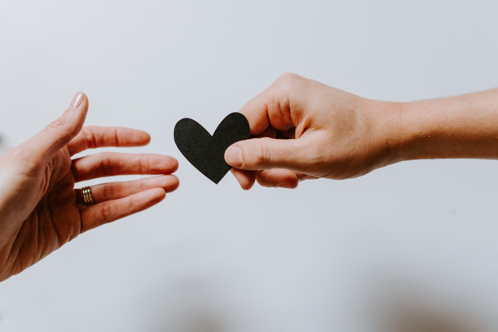 Two hands, one offering a paper heart to the other. Image by Kelly Sikkema, from Unsplash