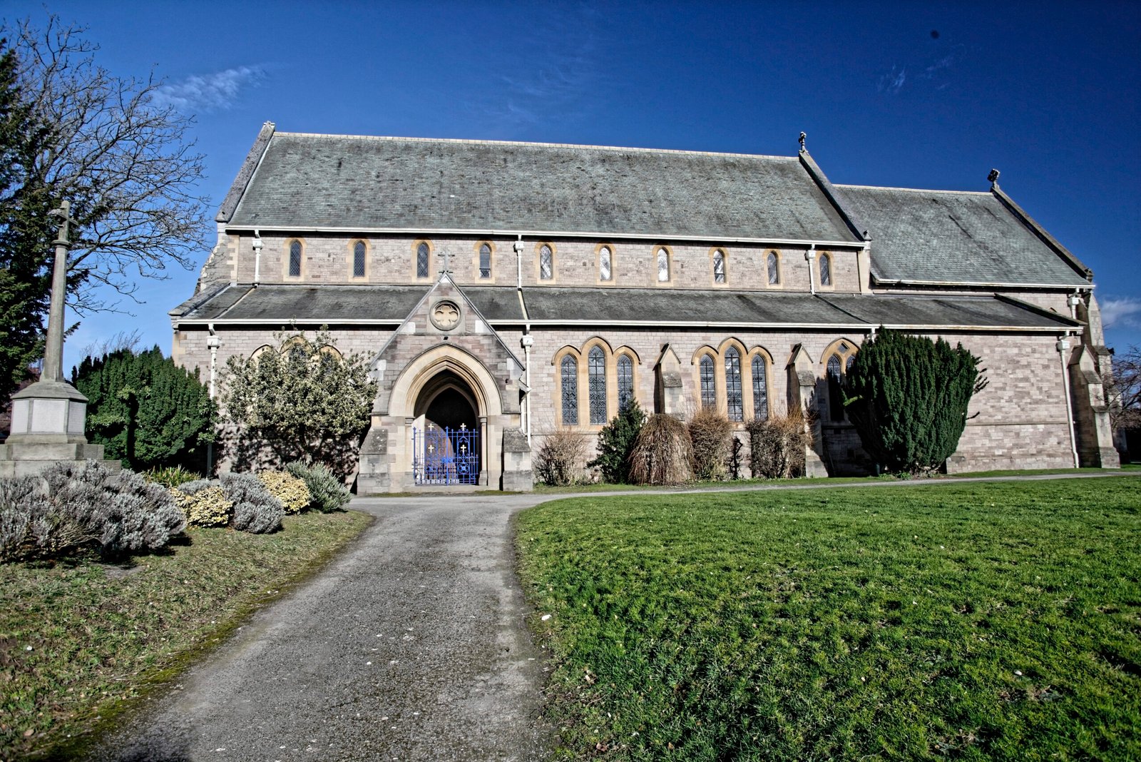 Stone church with arched windows and a blue gate, set against a blue sky.