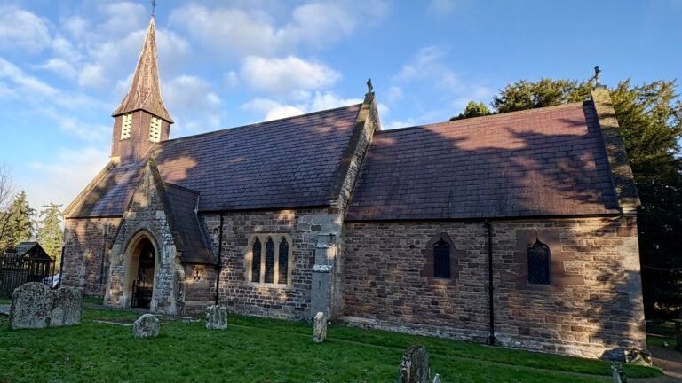 Stone church with a spire and gravestones on a sunny day