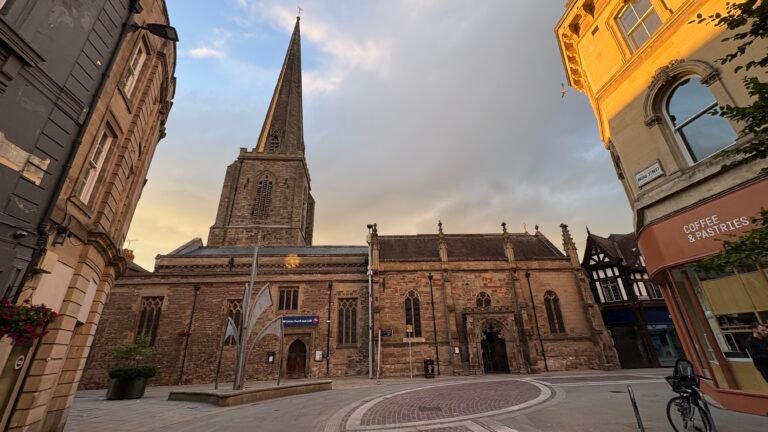 Historic church with a tall spire in a European town square, offering tours