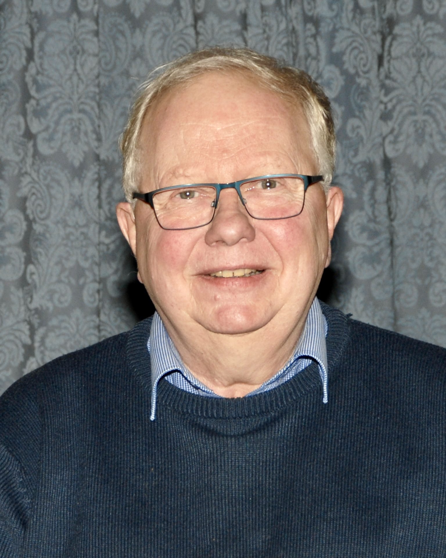David Thomson, a smiling man with glasses, wearing a blue sweater.