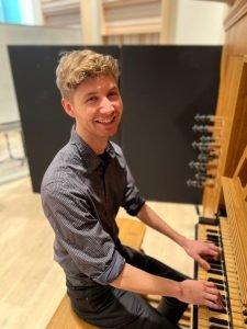 Director of Music, Ewan Murray, seated at an organ keyboard.