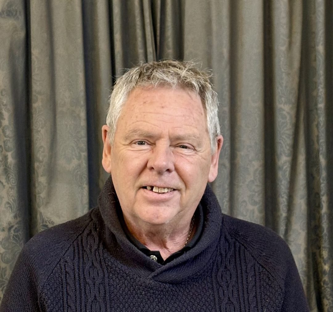 Mike Weaver, a man with gray hair, smiles in a dark sweater.