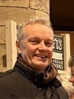 Michael Wild smiling, wearing a black jacket and scarf