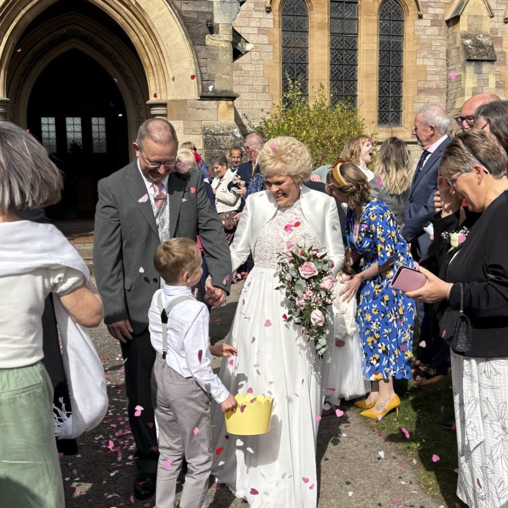 Bride and groom exiting church with flower petals, wedding celebration