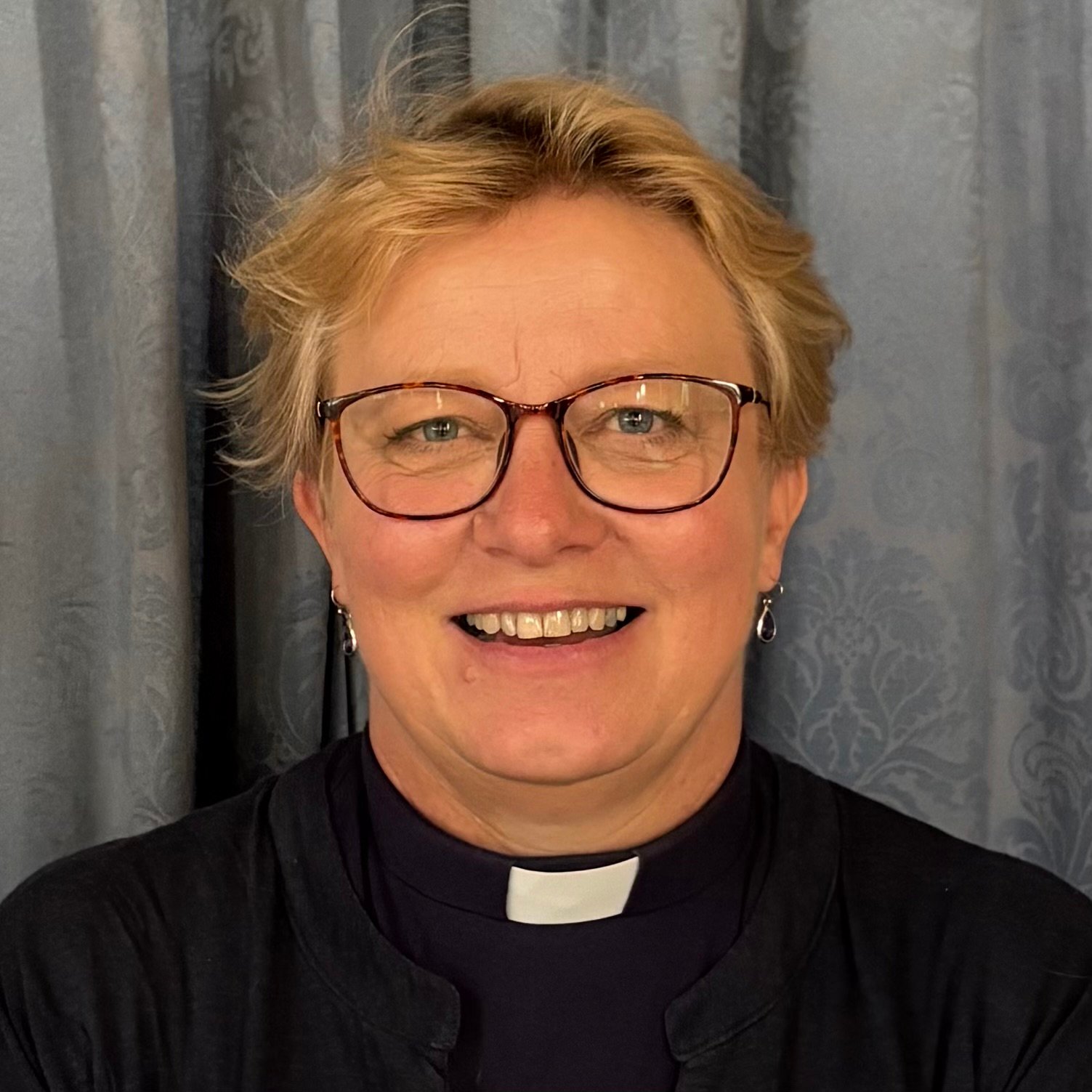 Christine Cattanach, a smiling woman wearing clergy attire and glasses.