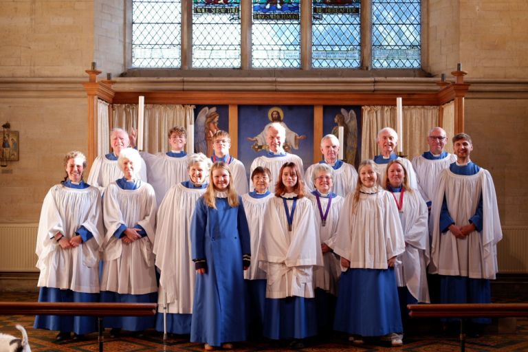 A choir group in blue and white robes stands in a church.